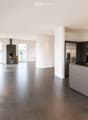 Modern kitchen with stainless steel appliances, dark grey cabinets, and a central island. Features a fireplace and large windows with a view of greenery.