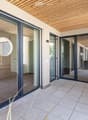 Modern balcony with large glass sliding doors, wooden ceiling, tiled floor, and circular mirrors on walls.