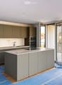 Modern kitchen with grey cabinets, central island, sink, and open sliding doors leading to a balcony.