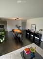 Modern open-plan living and dining area with a sofa, coffee table, dining table, chairs, cabinet, lamp, plant, and picture frame.