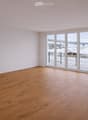 Empty room with wooden flooring and large sliding glass doors leading to a balcony with a view of a snowy landscape.