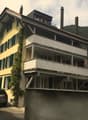 3-story yellow house, green shutters, brick chimneys, balcony on second floor, car parked in front