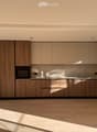 Modern kitchen with light wood cabinets, stainless steel oven, and wooden flooring.