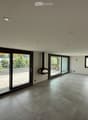 Empty room with tiled floor, large sliding glass doors leading to a balcony, and recessed ceiling lights.