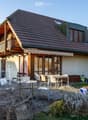 Detached house, brown roof, wooden balcony, solar panels, garden, outdoor dining area
