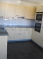 Modern kitchen with light-colored cabinets, dark tiled floor, granite countertop, and built-in oven.