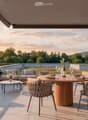 Balcony with a scenic view, featuring a sofa, coffee table, dining table, chairs, and decorative vases.