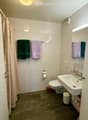 Modern bathroom with white tiled walls, dark grey tiled floor, toilet, sink, mirror, and towels.