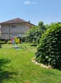 Well-maintained garden with a lawn, potted plants, a clothesline with laundry, and a small seating area with outdoor furniture.