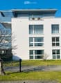 modern white house, 3 floors, large windows, balcony on the top floor, solar panels on the roof
