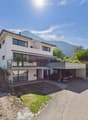 Two-story modern house with white exterior, large windows, balcony, garage, and scenic mountain view.