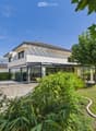 Modern two-story house with white exterior, large windows, and a spacious garden with well-maintained lawn and greenery.