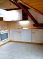 Modern kitchen with white cabinets, wooden accents, tiled walls, and a stainless steel sink and faucet.