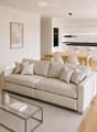 Modern living room with a light-colored sofa, glass coffee table, side table with a plant, dining area with a table and chairs, and a kitchen island with stools.