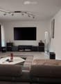 Modern living room with a grey sofa, coffee table, television, fan, and picture frame on the wall.
