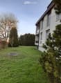 Lawn with trees and a modern house in the background.