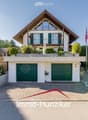 A two-story house with a modern design, featuring a garage, balcony, and well-maintained garden.