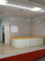 Modern office space with a reception desk, glass partitions, and striped wallpaper in the background.