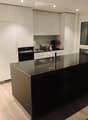 Modern kitchen with white cabinets, black countertops, stainless steel sink, and various appliances including an oven, toaster, and coffee maker.