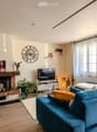 Modern living room with a blue sectional sofa, fireplace, television, coffee table, floor lamp, and decorative items.