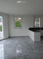 Modern kitchen with white cabinets, black countertop, marble flooring, and large windows letting in natural light.