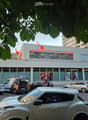 Modern building with large windows and a 'coop' sign, surrounded by parked cars and pedestrians.