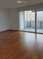 Empty room with wooden flooring and large sliding glass doors leading to a balcony.