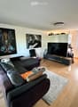Modern living room with a dark grey sectional sofa, coffee table, flat-screen TV, and decorative artwork on the walls.