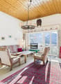 Cozy living room with a fireplace, large window offering a mountain view, sofa, armchairs, coffee table, television, and decorative items.