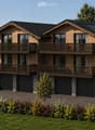 Two-story wooden house with multiple balconies, large garage, and landscaped surroundings.