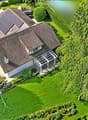 Aerial view of a house with a well-maintained garden, swimming pool, patio furniture, and a covered outdoor seating area.