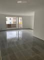 Empty room with dark tiled floor and large sliding glass doors leading to a balcony.