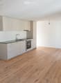 Modern kitchen with light-colored cabinets, a black countertop, and a wooden floor. The kitchen features a sink, oven, and ample storage space.