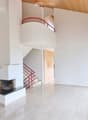 Bright hallway with a modern fireplace, wooden ceiling, large windows, and a red staircase leading to an upper level.