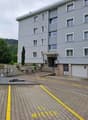 Gray building, multiple windows, garage door, steps leading up, gravel in front, yellow parking lines