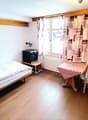 single bed, bedside table, TV, table, chair, window with curtains