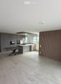 Modern kitchen and dining area with grey cabinets, a central island, a wooden dining table, and a sleek oven. The space features large windows and a contemporary design with a mix of wood and metal finishes.