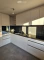 Modern kitchen with white cabinets, black countertops, and stainless steel appliances, including a sink and oven.