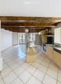 Bright, open kitchen with tiled flooring, wooden cabinets, stainless steel appliances, and a central island.