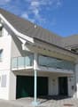 modern white house, gray roof, glass balcony, garage, paved driveway