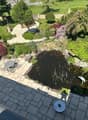 Well-maintained garden with a pond, seating area, and various plants and trees.