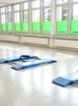 Empty room with large windows, white walls, and a smooth concrete floor. Contains blue ramps and a small machine on the left side.