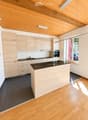 Modern kitchen with light wooden cabinets, dark granite countertop, and a central island. Features include a sink, oven, and pendant lighting.