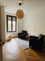 A room with two armchairs, a coffee table, a carpet, a floor lamp, and a window with view to outside.