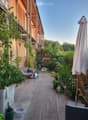 Balcony with tiled floor, sofa, umbrella, various potted plants, and decorative items.
