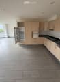 Modern kitchen with light wood cabinets, stainless steel appliances, and large windows letting in natural light.