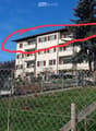 A fenced yard with grass, a playground structure, and surrounding residential buildings.