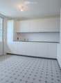 Modern kitchen with white cabinets, a built-in oven, and a sleek faucet. The floor features a geometric tile pattern in gray and white.