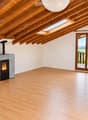 Bright, airy attic space with wooden beams, skylights, and a fireplace. Large sliding glass doors open to a balcony with scenic views.