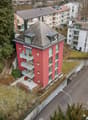 3-story red building with balconies and a gray roof
